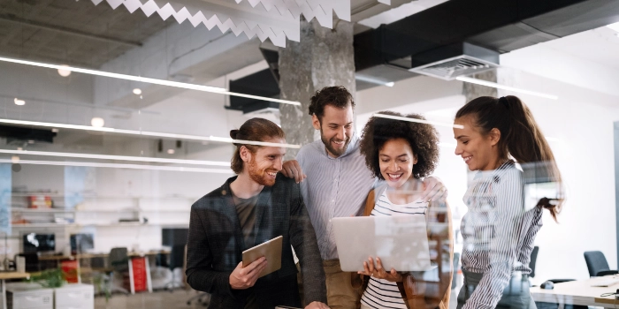 Eine gemischte Gruppe Mitarbeitender aus dem Bereich Test & Quality Management betrachten Arbeitsergebnisse auf einem Laptop