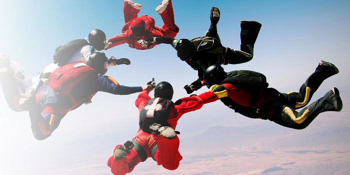 Mehrere Fallschirmspringer während ihres Sprungs symbolisieren den Mut von msg advisors