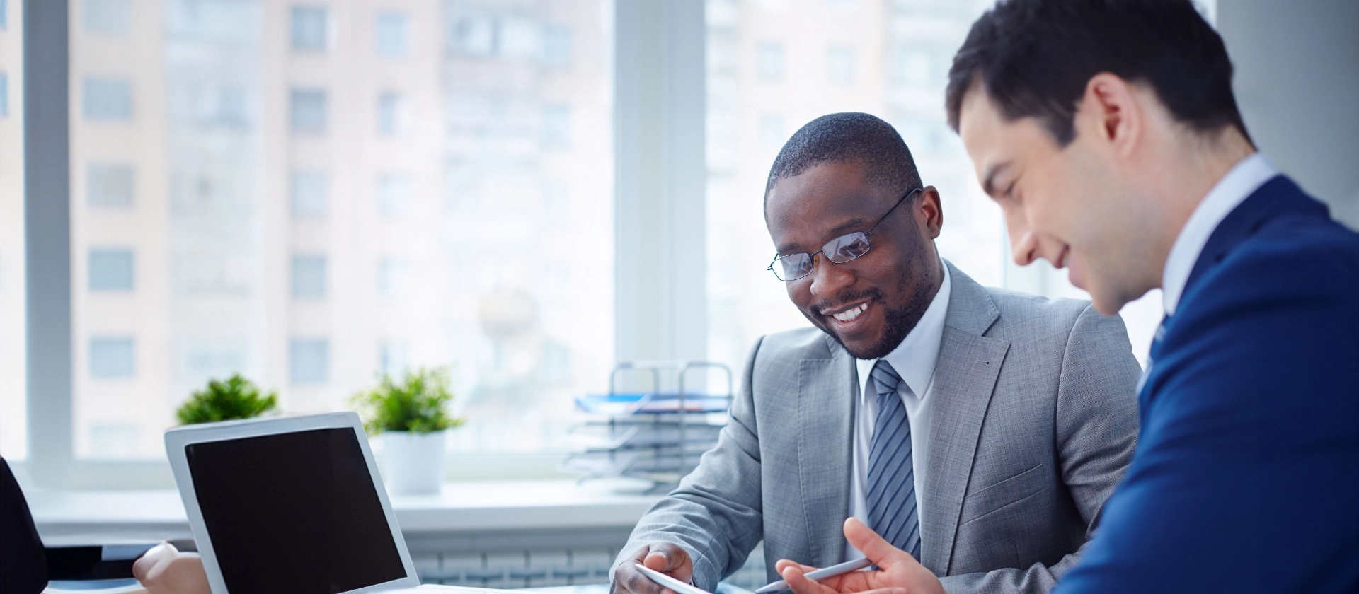 Zwei Business-Partner am Tisch mit Tablet, Statistiken und Zahlen