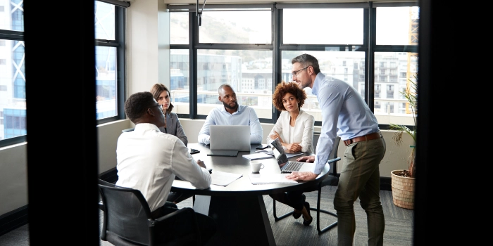 Eine gemischte Gruppe erfahrener Cloud-Mitarbeitenden besprechen sich in einem Meetingraum